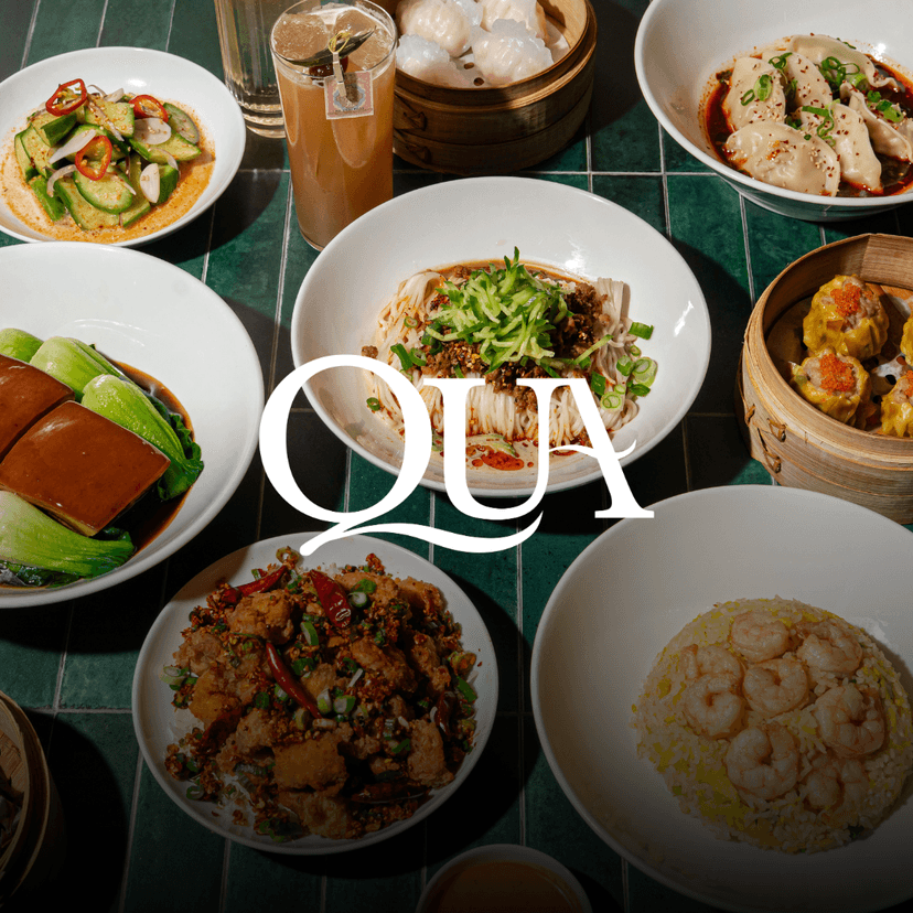 QUA Contemporary Chinese Cuisine logo overlaid an overhead spread from QUA Contemporary Chinese Cuisine showcasing shrimp fried rice, spicy cucumber salad, shumai, chili wontons, chicken cartilage with mala BBQ spice, abalone sticky rice, braised Dong Po pork belly, and dan dan noodles arranged across a deep green tiled table.